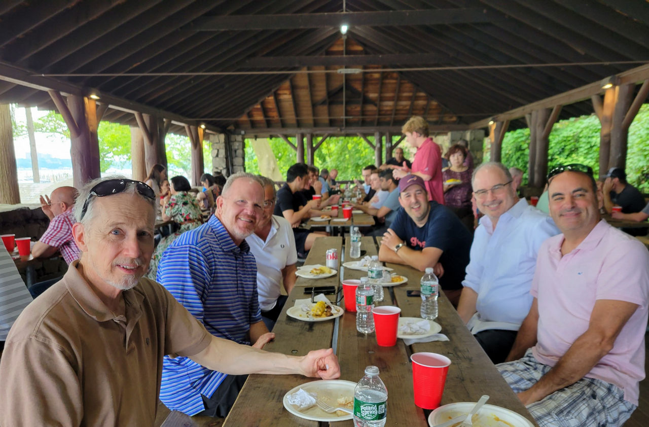 People sitting at a long table at the company barbecue event